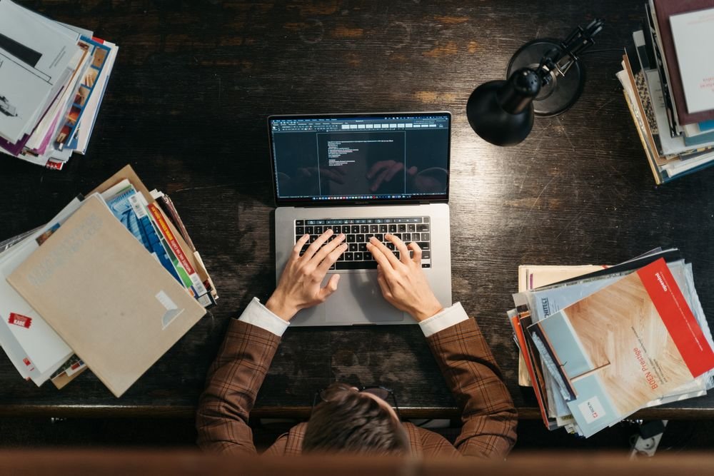 باحث يعمل على حاسوب محمول تحيط به كتب وملفات مرجعية